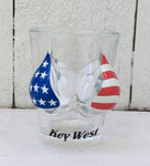 Shot glass shaped like a woman bust wearing an American flag bikini top. With "Key West" label.