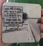 Hardboard Coaster showing a mid 20th century picture of a Sate Road sign located on US1: "YOU ARE LEAVING KEY WEST FLORIDA, THE BEGINNING OF U.S. ROUTE No. 1 AND ENDING IN FORT KENT ME.", "Thank you - Come again - Sate Road Dept."