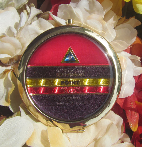 Compact Mirror picture showing a golden design in the style of the Southernmost Point.
