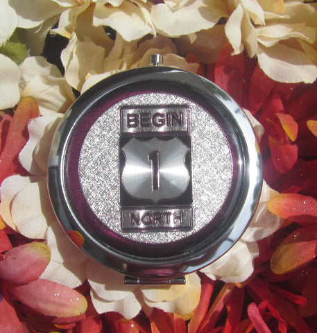 Compact Mirror picture showing a silver design of the US 1 sign "Begin" and "North".