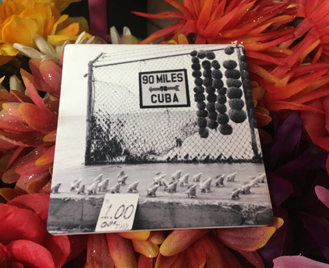 Sandstone Coaster showing a mid 20th century black and white picture of a "90 MILES TO CUBA" sign with an arrow pointing out to the sea and conch shells lined up on the cement, for sale at only $1 each! 