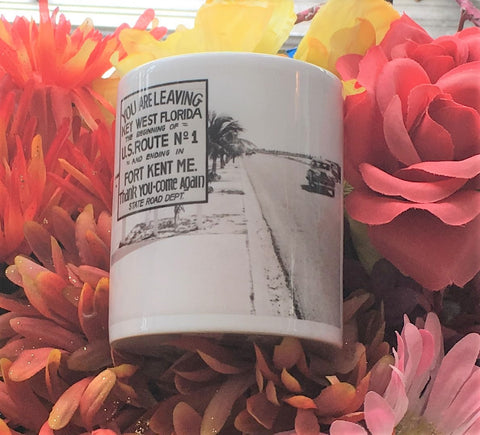 Front view mug showing a mid 20th century picture of a Sate Road sign located on US1: "YOU ARE LEAVING KEY WEST FLORIDA, THE BEGINNING OF U.S. ROUTE No. 1 AND ENDING IN FORT KENT ME.", "Thank you - Come again - Sate Road Dept."