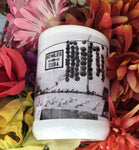 Front view mug showing a mid 20th century black and white picture of a "90 MILES TO CUBA" sign with an arrow pointing out to the sea and conch shells lined up on the cement, for sale at only $1 each! 