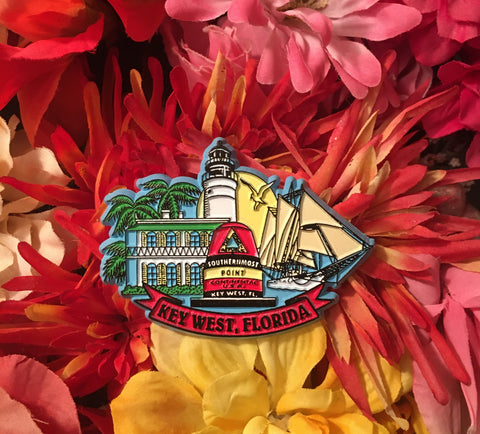 Magnet showing the Southernmost Point, the Hemingway House, the Lighthouse, a schooner, a sunset and palm trees. With "Key West, Florida".