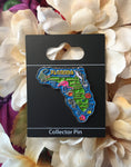 Pin on display card "Collector Pin" showing the map of Florida with popular destination towns, Floridian animals (alligator, flamingo, manatee, dolphin, fish), a conch shell, an hibiscus flower, an orange with leaf and "FLORIDA".