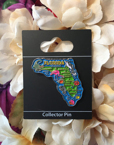 Pin on display card "Collector Pin" showing the map of Florida with popular destination towns, Floridian animals (alligator, flamingo, manatee, dolphin, fish), a conch shell, an hibiscus flower, an orange with leaf and "FLORIDA".