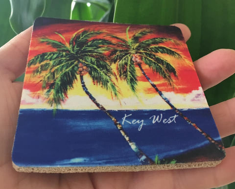 Rubber Coaster picture showing a painting of palm trees in front of a sunset waterview.