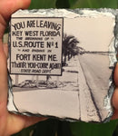 Slate Coaster showing a mid 20th century picture of a Sate Road sign located on US1: "YOU ARE LEAVING KEY WEST FLORIDA, THE BEGINNING OF U.S. ROUTE No. 1 AND ENDING IN FORT KENT ME.", "Thank you - Come again - Sate Road Dept."