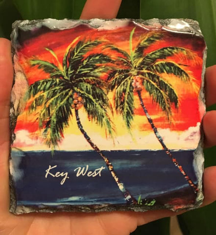Slate Coaster picture showing a painting of palm trees in front of a sunset waterview.