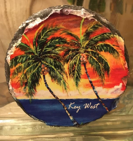 Slate Coaster round picture showing a painting of palm trees in front of a sunset waterview.