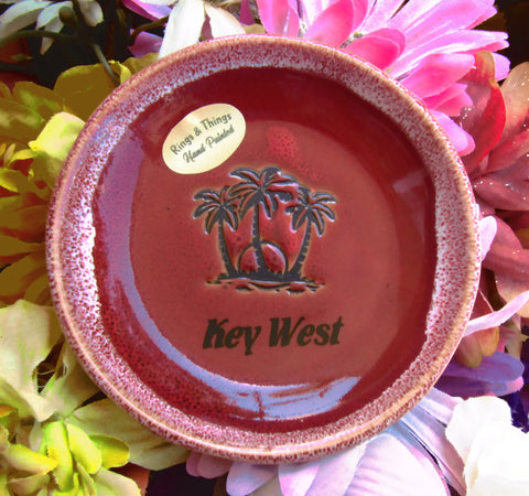 Red color glaze dish showing palm trees and sunset, with "Key West".