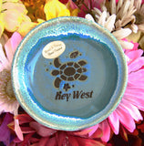 Blue color glaze dish showing a sea turtle, a tiny fish and a seashell, with "Key West".