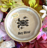 Natural color glaze dish showing a sea turtle, a tiny fish and a seashell, with "Key West".