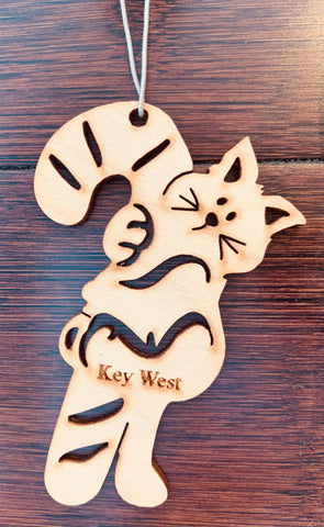 Wood ornament in the shape of a kitty holding on to a sugarcane as big as itself. With "Key West".