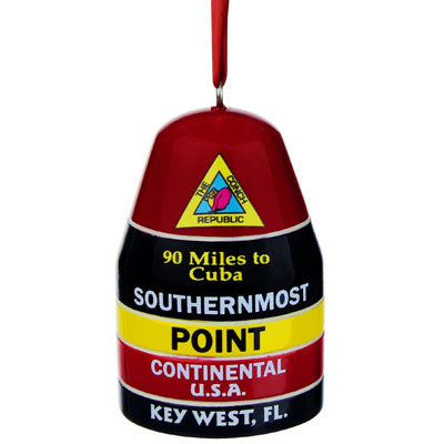 Ornament showing a figurine of the Southernmost Point (held by a red ribbon): at the top, a triangular design showing a conch shell and "The Conch Republic" (red background), then underneath "90 Miles to Cuba" and "SOUTHERNMOST" with a black background, then underneath "POINT" with a yellow background, then underneath "CONTINENTAL U.S.A." with a red background and finally at the bottom "KEY WEST, FL" with a black background.