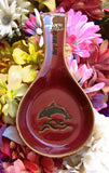 Red color spoon rest showing a jumping dolphin, with "Key West" on the handle.